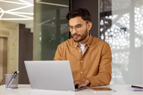 Homem em um escritório e em frente a um computador de mesa.